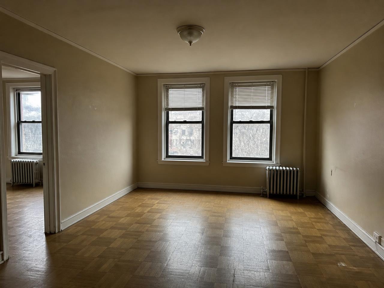 Bedford-Stuyvesant living room before interior design, empty with worn carpet and dated ceiling fan